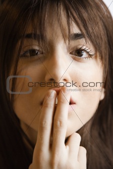 Woman holding finger to mouth.