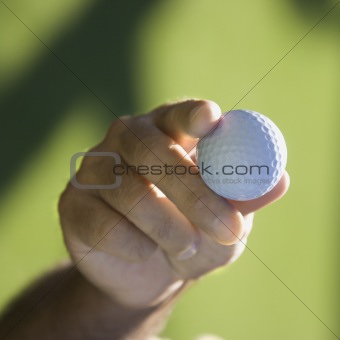 Hand holding golf ball.