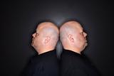 Bald twin men back to back.