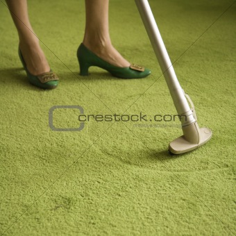 Woman vacuuming rug.