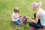 Blond Mother showing her daughter a purple flower 