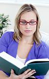 Young woman with glasses reading a book
