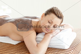 Radiant woman enjoying a mud skin treatment 