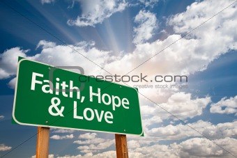 Faith, Hope and Love Green Road Sign with Dramatic Clouds, Sun Rays and Sky.