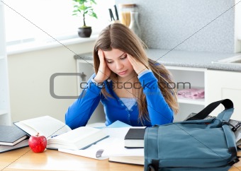Happy female teenager studying in the kitchen