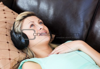 Young woman lies on a sofa and listen music