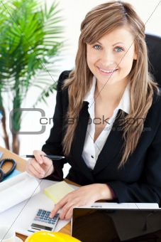 Smilling businesswoman working in her office with a calculator