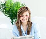 Glowing woman with glasses reading newspaper
