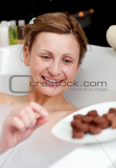 Bright woman eating chocolate while having a bath
