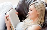 Charming woman reading a book sitting on a sofa 