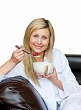 Charming woman eating cereals on the sofa