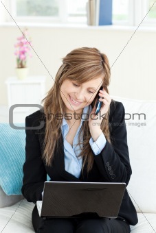 Glowing businesswoman using her phone and laptop