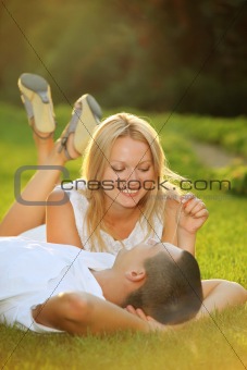 Young happy couple lying down on grass in the sun