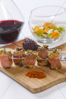 Beef served on skewers with condiments and red wine