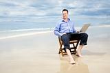 business man sitting on a chair on the beach with laptop