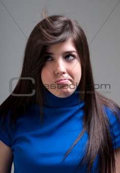 Young girl bored blowing hair on grey background