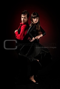 Young couple passion flamenco dancing on red light background.