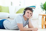 Young man with headphones lying on the floor in the living room