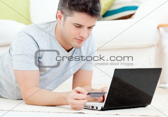 Concentrated man holding a credit card looking at a laptop