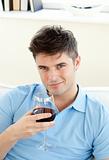 Handsome young man sitting on a sofa holding wineglass