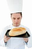 A male cook with closed eyes smell at  bread