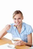 Delilghted woman eating cereals sitting at a table