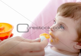 mother feeding baby yellow spoon