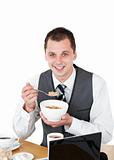 Smiling businessman eating cereals looking at the camera
