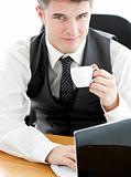 Jolly young businessman looking at the camera holding a coffee