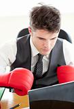 Ambitious businessman wearing boxing gloves in the office 
