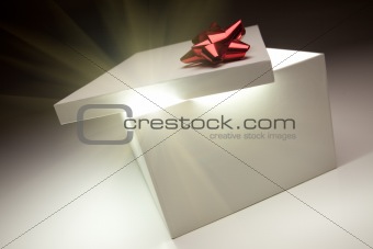 Gift Box with Red Bow Lid Revealing Very Bright Contents on a Gradated Background.