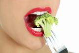Broccoli on steel fork in woman mouth