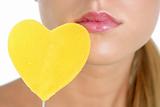 Heart shape candy on woman macro mouth