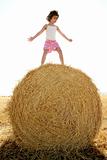 Girl playing over the round wheat dried bale