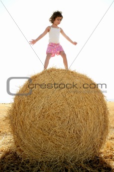 Girl playing over the round wheat dried bale