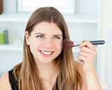 Radiant woman using a powder brush at home