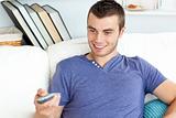 Cute man is relaxing in the living-room with remote