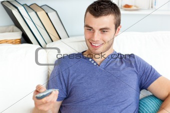 Cute man is relaxing in the living-room with remote
