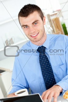 Handsome businessman using a laptop in the kitchen