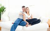 Adorable couple using a remote in the living-room