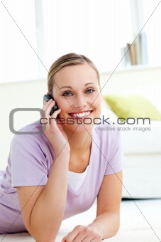 Attractive woman talking on phone lying on the floor