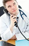 Handsome male doctor talking on the phone in his office