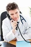 Attractive male doctor talking on the phone in his office