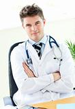 Handsome male doctor with folded arms sitting in his office
