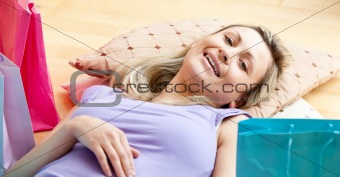 Happy woman after shopping lying on the floor in a living-room