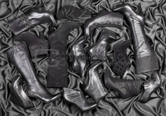 Female black shoes and boots placed on black satin