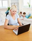 Busy woman working with her children at laptop
