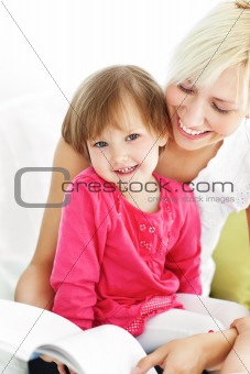 Smiling mother reading a book with children