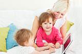 Smiling woman working with her children at laptop