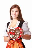 Woman in love dressed with Oktoberfest dirndl holding gingerbread heart